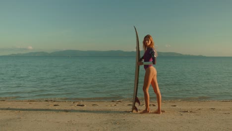 woman with surfboard on the beach at sunset
