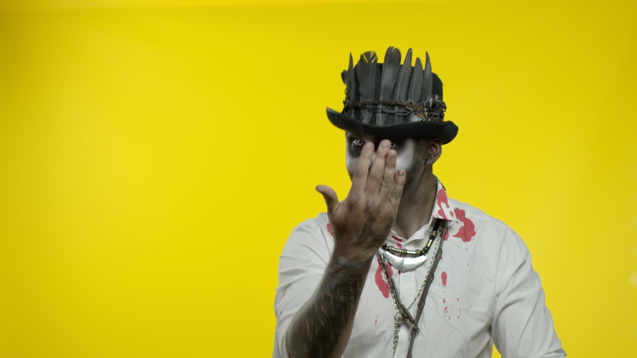 hombre espeluznante con maquillaje de esqueleto mirando a la cámara, tratando de asustar, señalando a la izquierda. halloween