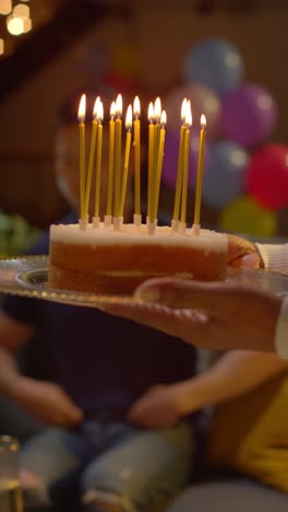 Vertical-Video-Close-Up-Of-Woman-Holding-Birthday-Cake-Decorated-With-Lit-Candles-At-Party-At-Home