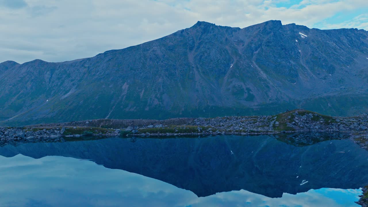 Bjergtoppe spejlet i en rolig sø ved vandrestier nær Sør-Tverrfjord i Loppa, Nordnorge. Luftfoto.