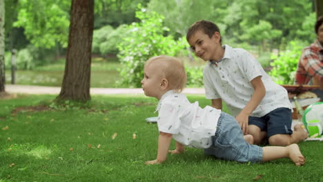 adorable toddler falling on grass in park. parents laughing with kids outdoors