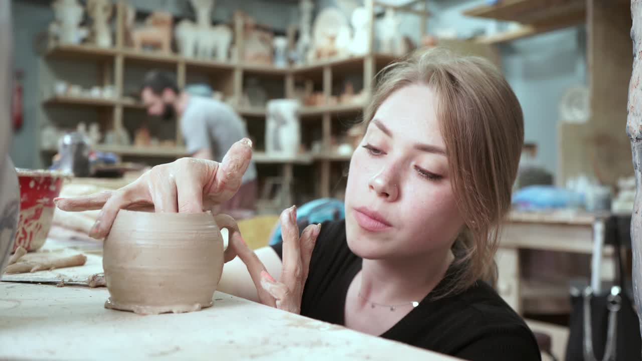 молодая женщина делает кувшин из глины. женские руки формируют керамику