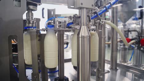 robotic dairy plant indoors. automatic equipment for covering plastic bottles with milk in a modern factory. process of putting plastic lids on bottles.