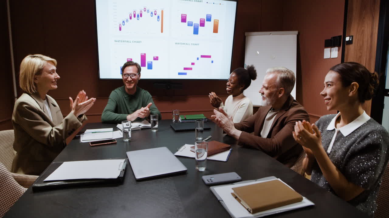 Professionals Collaborating and Clapping During a Business Meeting with Data Presentation