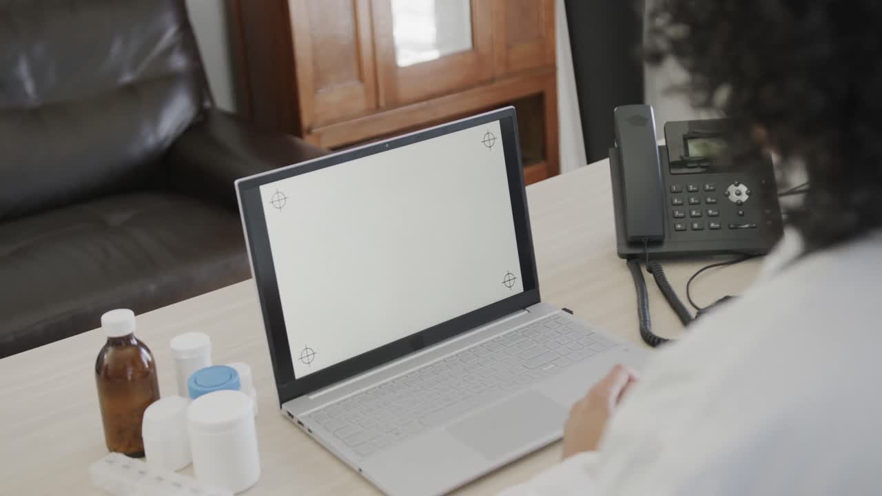 책상에 앉아서 복사 공간이 있는 노트북을 사용하는 두 인종의 여성 의사, 슬로우 모션