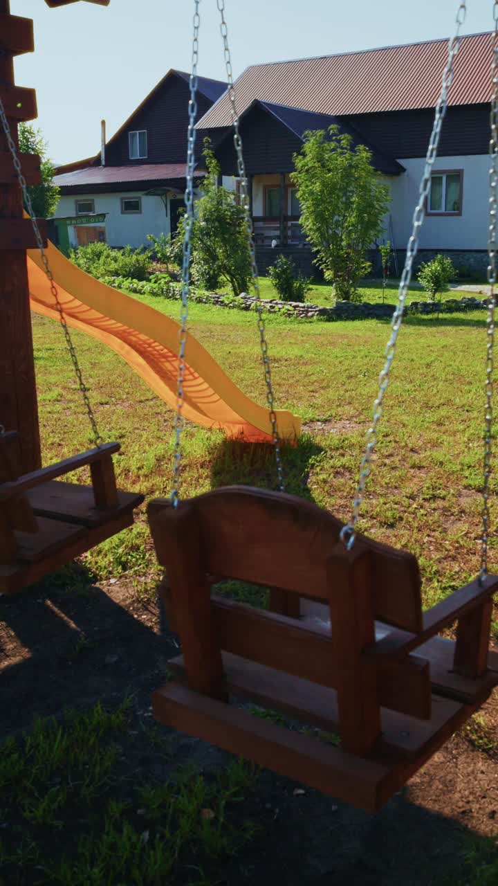 Empty Wooden Swing Set Swaying Gently in a Sunny Backyard