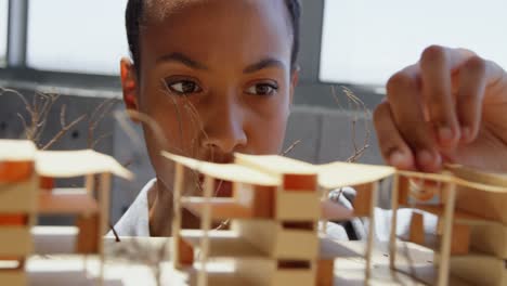 vista frontal de una mujer de negocios afroamericana mirando un modelo arquitectónico en una oficina moderna 4k