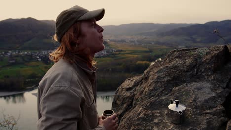 young man with long hair drinking coffee looking to stunning landscape, vogelberg