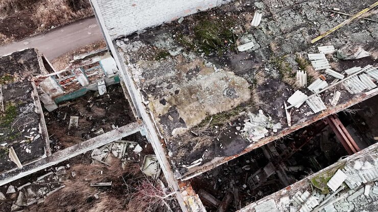 Remains of an old buildings with some broken parts. Shooting in motion on the area of an abandoned plant. Aerial perspective.