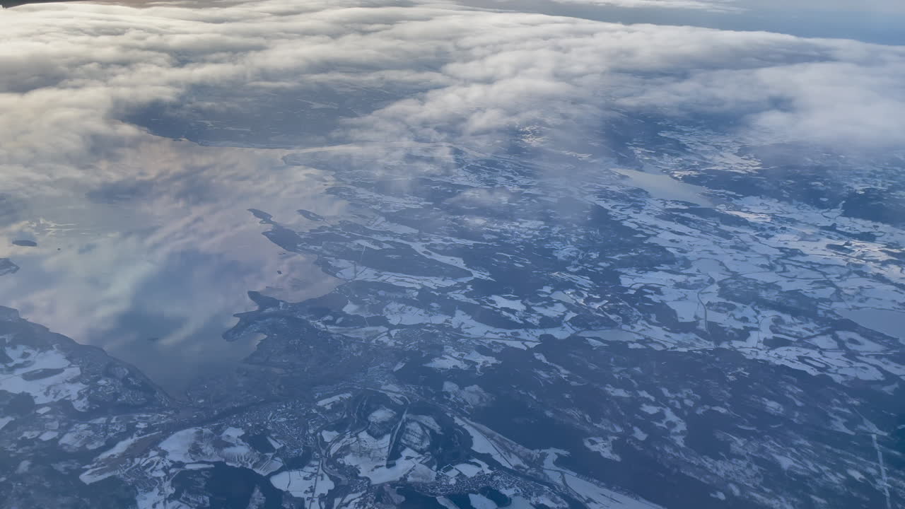 deslizándose por encima de las nubes sobre el fiordo de trondheim con un sol dorado brillante que contrasta con el suelo nevado azul y el cielo reflejado en el agua, toma panorámica de derecha a izquierda