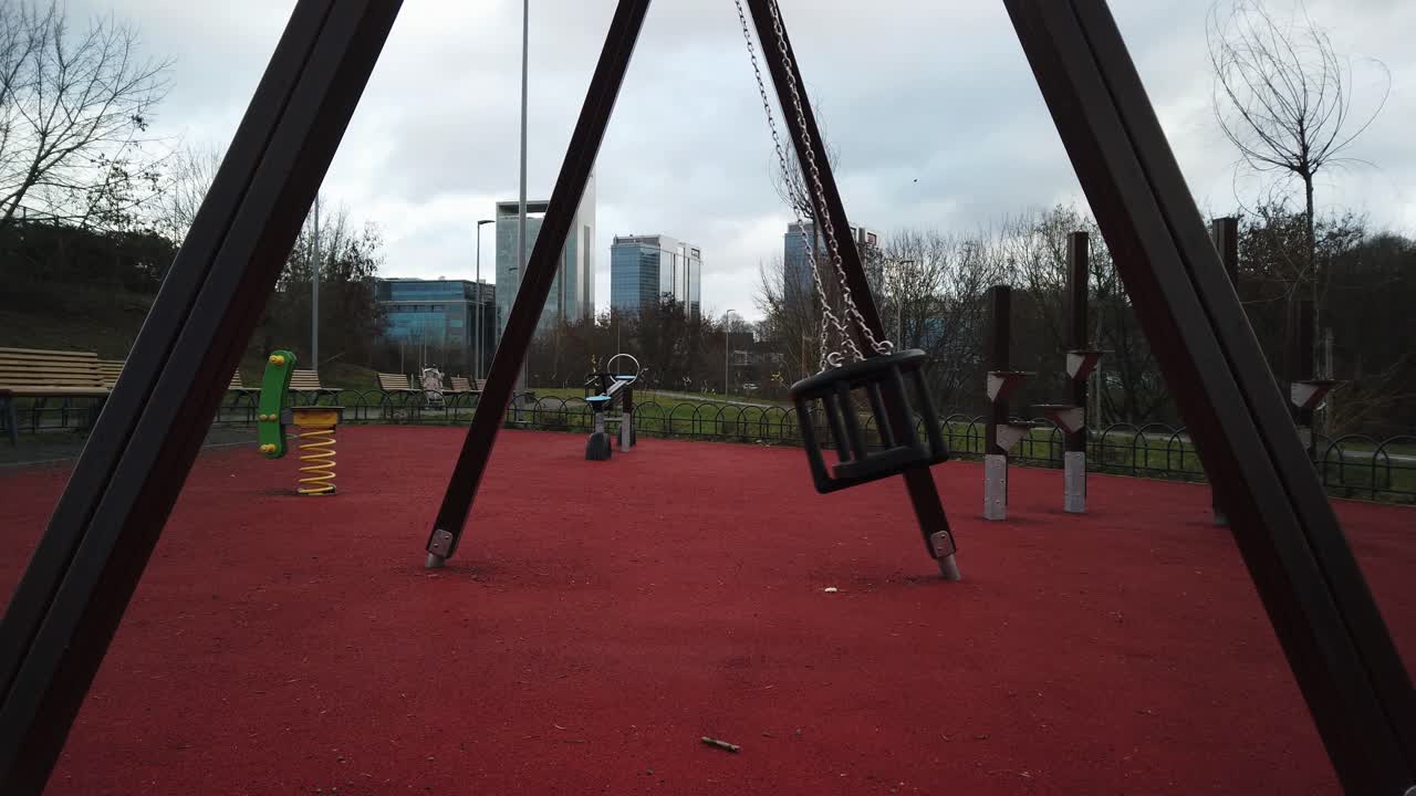 Le altalene di un parco giochi solitario oscillano durante una giornata nuvolosa a Vilnius, Europa settentrionale, Lituania.