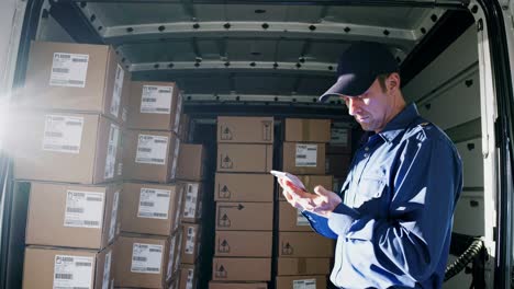 side angle video of a delivery worker in a van, checking a smartphone