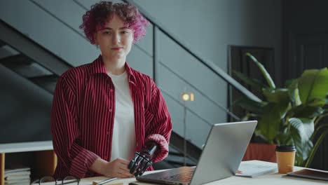 portrait of smiling girl with prosthetic arm sitting at desk in office