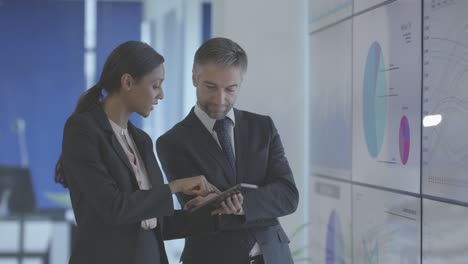 businessperson meeting in boardroom referencing spreadsheet data on big screen