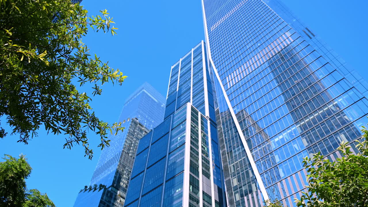 Grattacielo di vetro che riflette un cielo azzurro limpido. Architettura di grattacieli di New York, USA. Vista dal basso verso l'alto