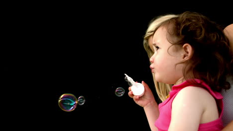 Cute-little-girl-blowing-bubbles-with-mother