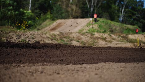 motocross racer passing by on motorcycle splashing mud riding bike on dirt track during championship race in slow motion