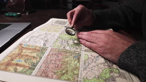 researcher studies old geographical atlas map archive with magnifier