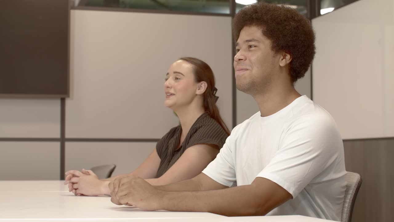 un hombre afroamericano de unos 20 años y una mujer caucásica de unos 20 anos hablando en una reunión de negocios con dolly en video.