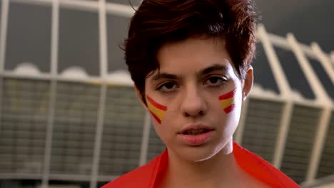 portrait of a young brunette girl soccer fan in spain, looking at the camera, serious face, evening stadium in the background 50 fps