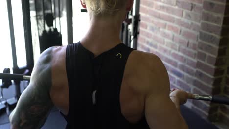 Tattoo-man-muscles-in-home-gym-rowing-shot-from-behind