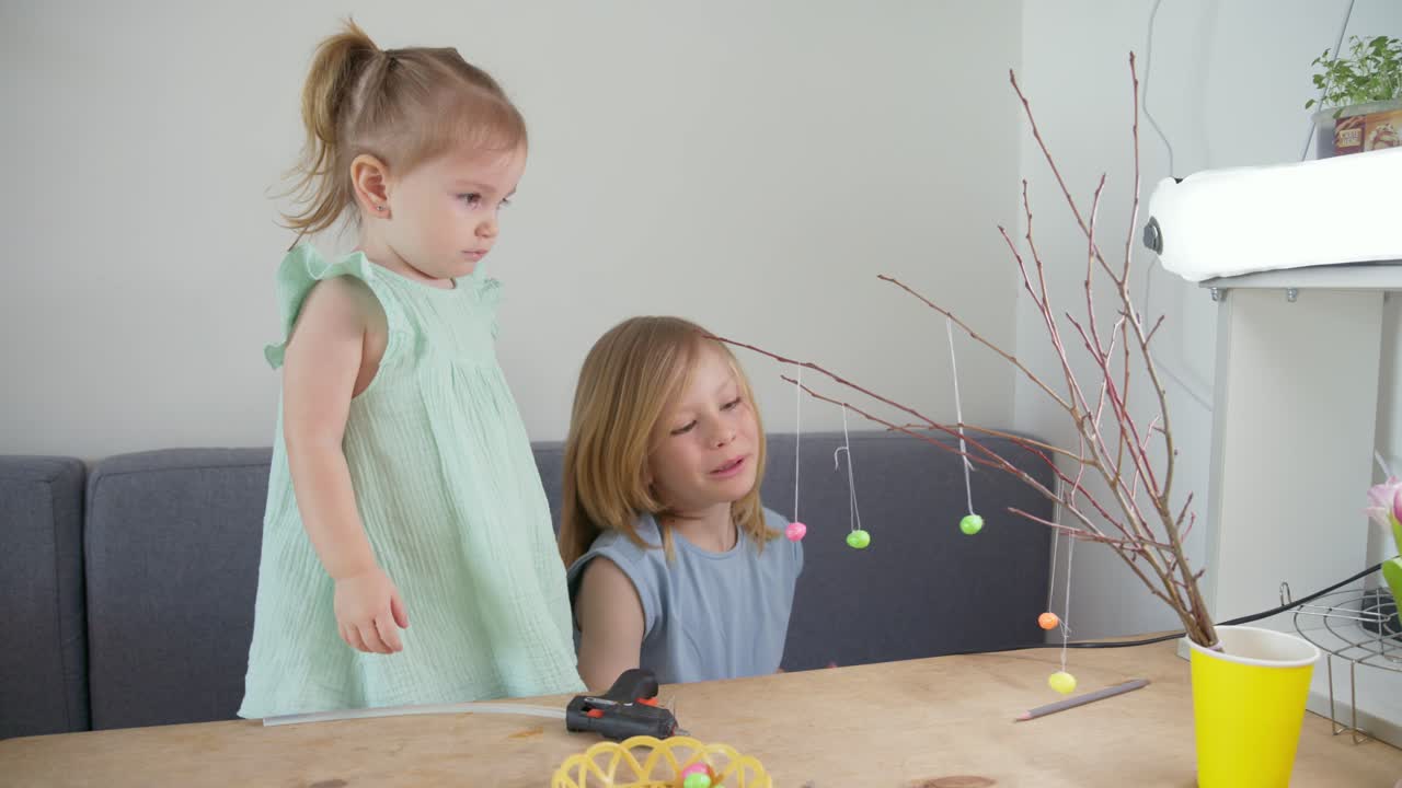 Two Young Girls Decorating Easter Branches with Colorful Eggs
