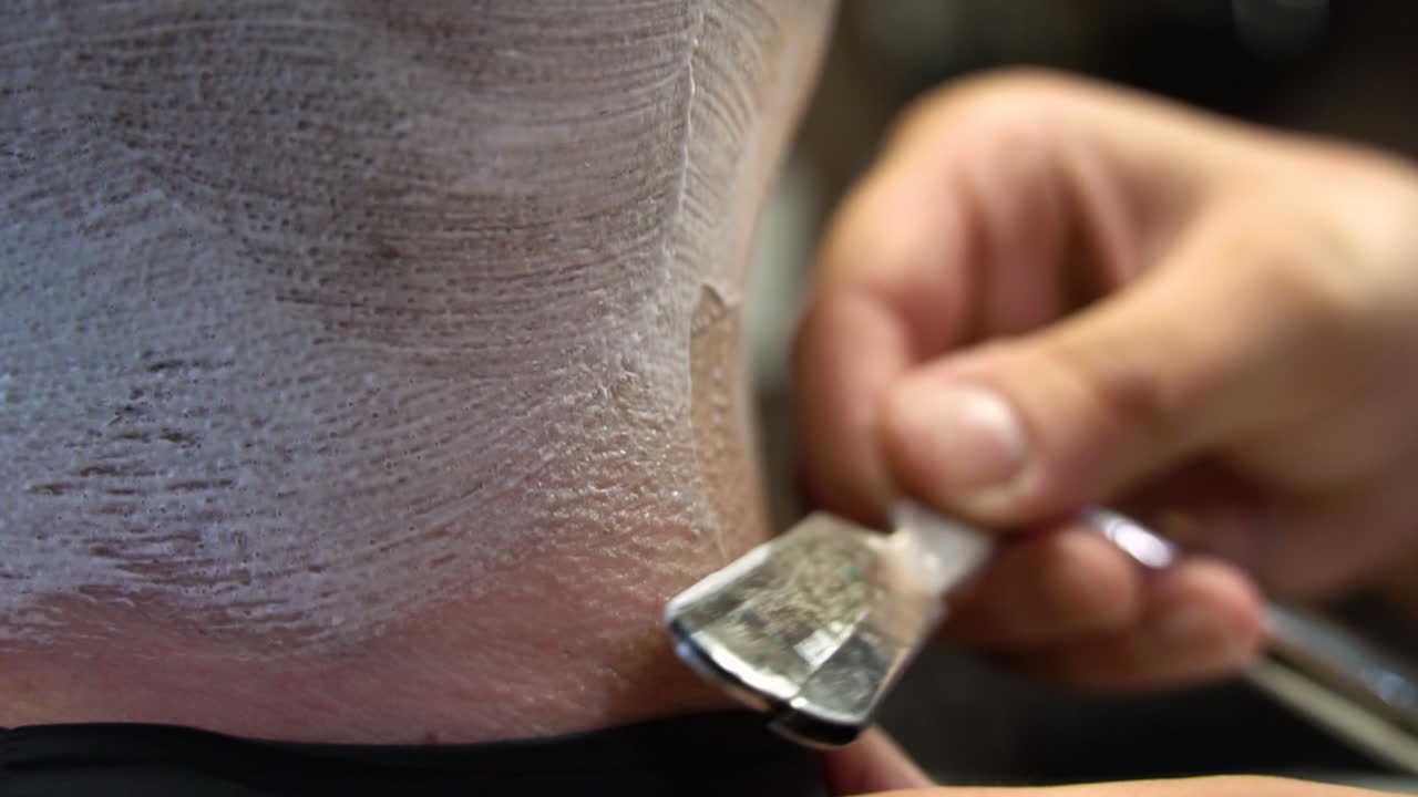 Close-up view of a barber shaving a man's neck with a straight razor