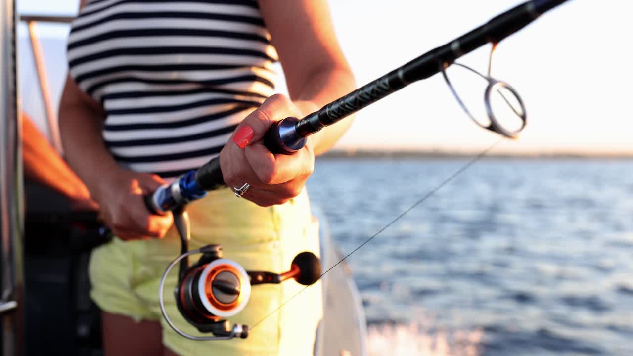 Primo piano di una persona che tiene una canna da pesca su una barca