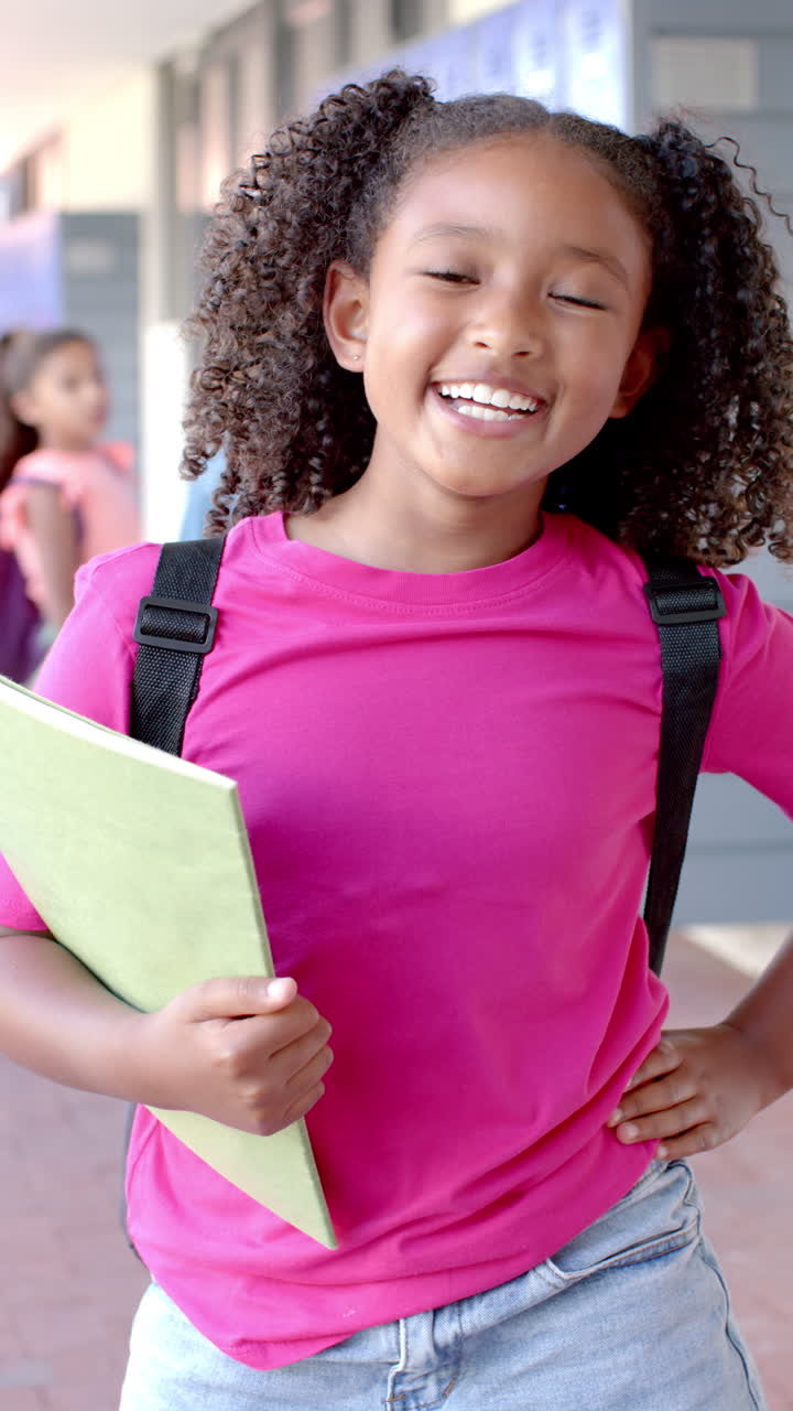 Vertical video: In school, young girl holding a folder is laughing