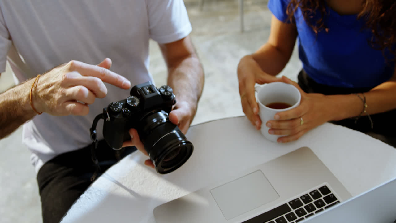 Fotógrafo y modelo discutiendo frente a un portátil 4k.