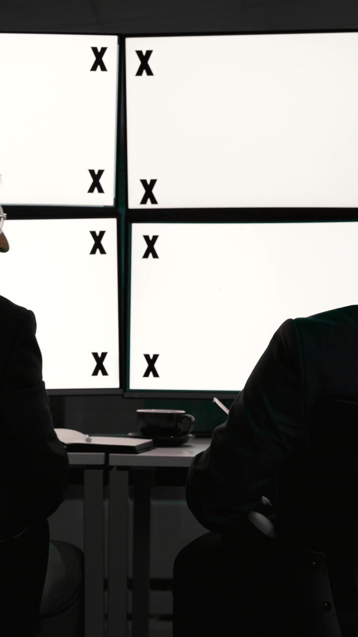 Due uomini d'affari che si danno il cinque davanti a grandi monitor del computer