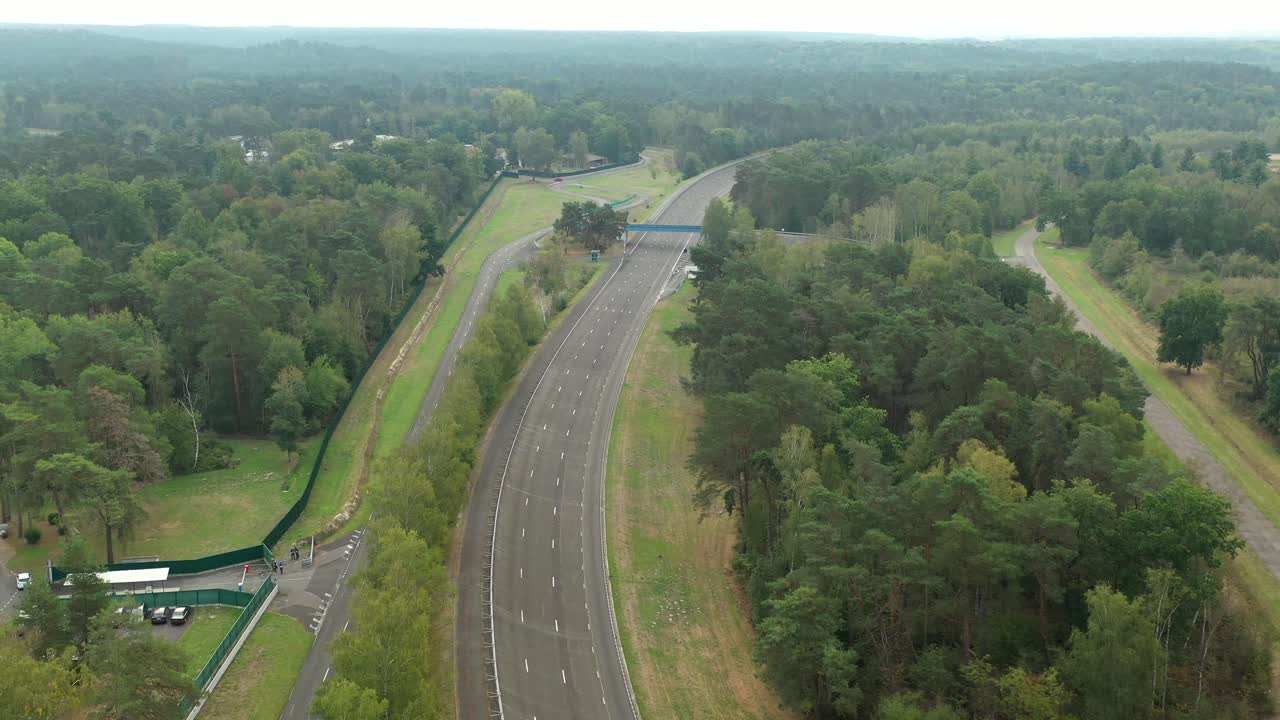 Aerial view of empty UTAC Mortefontaine race track winding through dense forest landscape, France