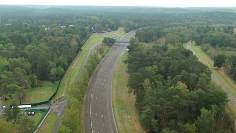 aerial view of empty utac mortefontaine race track winding through dense forest landscape, france
