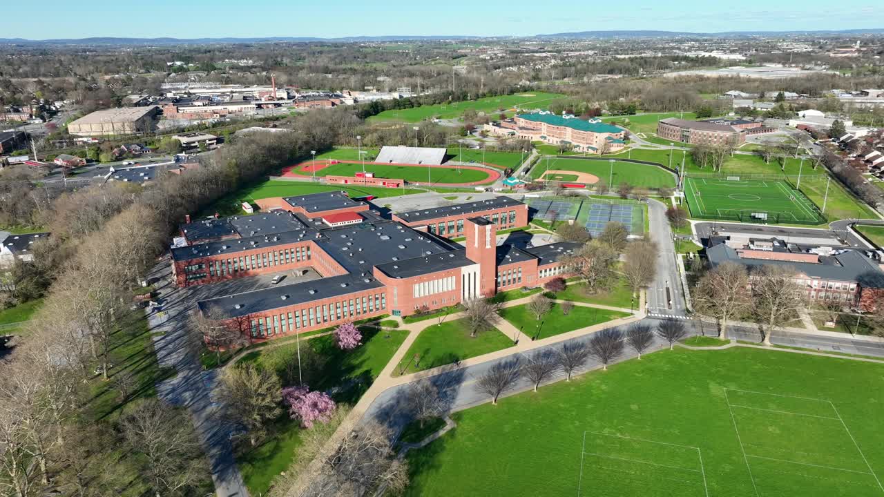 Aerial top down of sport fields on american high school during sunny day. Leafless trees in suburb neighborhood of Pennsylvania.