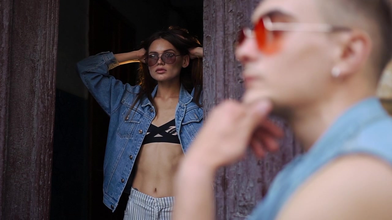 Coppia giovane ed elegante in posa con giacche di jeans all'aperto