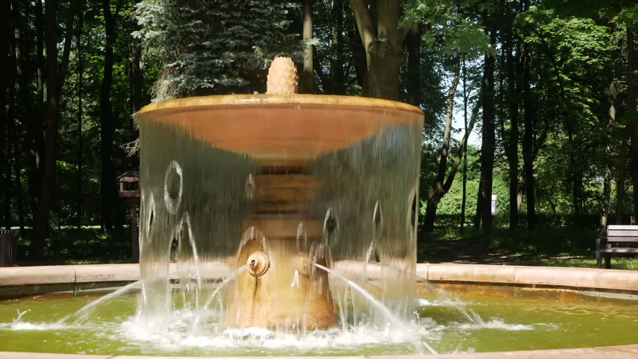 A small fountain with water in the summer park - a place of rest from the heat