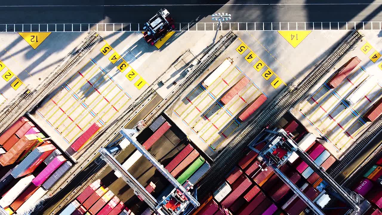 Industrial vehicles moving and sorting shipping containers at busy shipping port near New York City - top down aerial footage