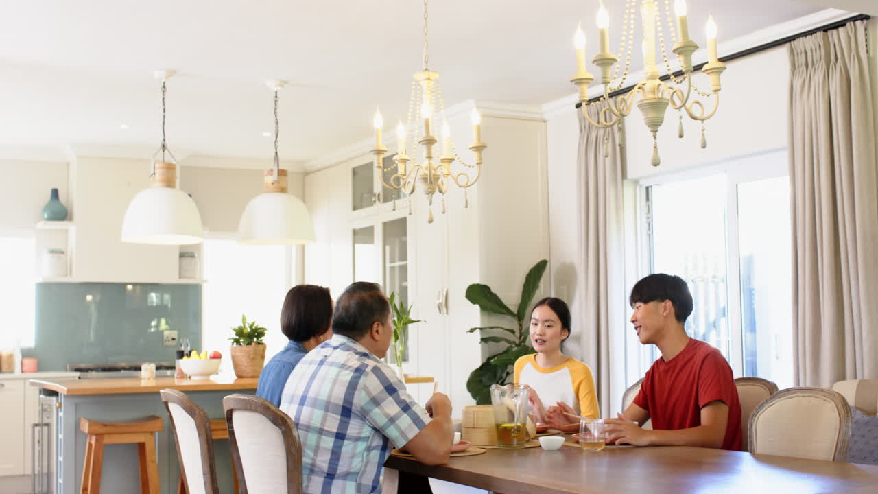 Family enjoying meal together, sitting at dining table in bright kitchen