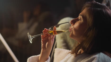 gloomy woman lost in thoughts takes sip of light alcoholic drink. deep gaze of woman falls on glass held in own hands but lady looks as if through beverage