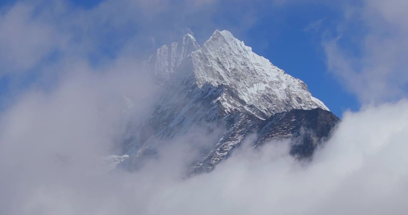 Everest-regionen, Nepal, statisk luftfoto af den ikoniske sneklædte top af Mount Ama Dablam, der bryder igennem langsomme skyer på en lys dag