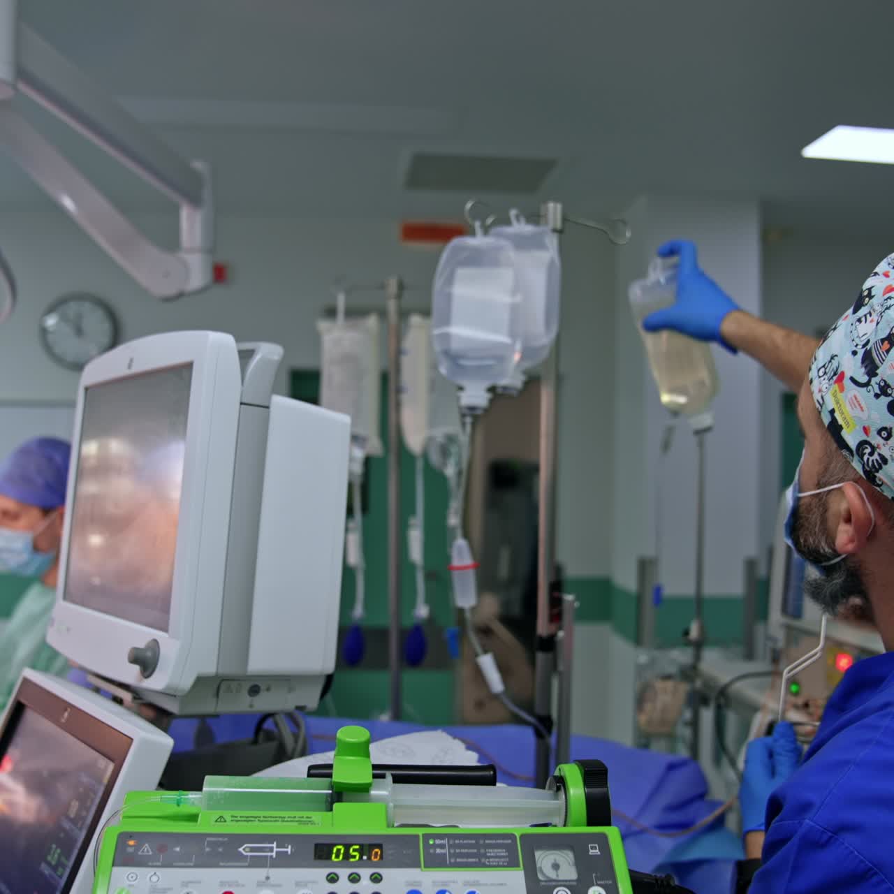 Uniformed male anesthesiologist come up to a drop counter stand. Doctor hangs the bottle with medicine on the hook