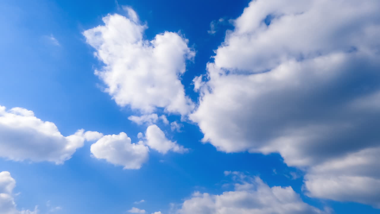 Soft cotton clouds transforming in the sky. Sun lighting the white cloudscape in atmosphere. Low angle perspective. Timelapse.