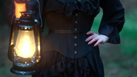 Girl-in-a-corset-and-a-black-dress-holds-a-kerosene-lamp-with-a-flame