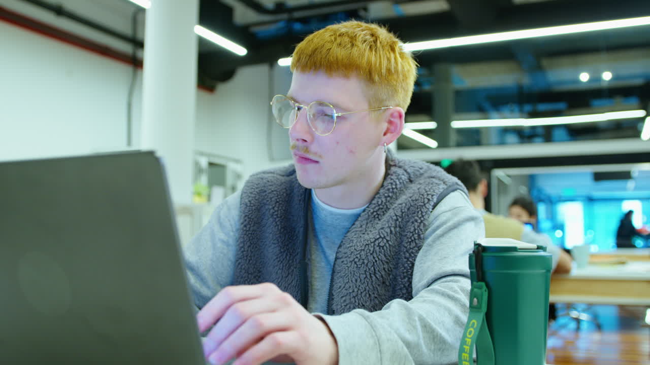 Young Gen Z Man Working on Laptop at Desk in the Office