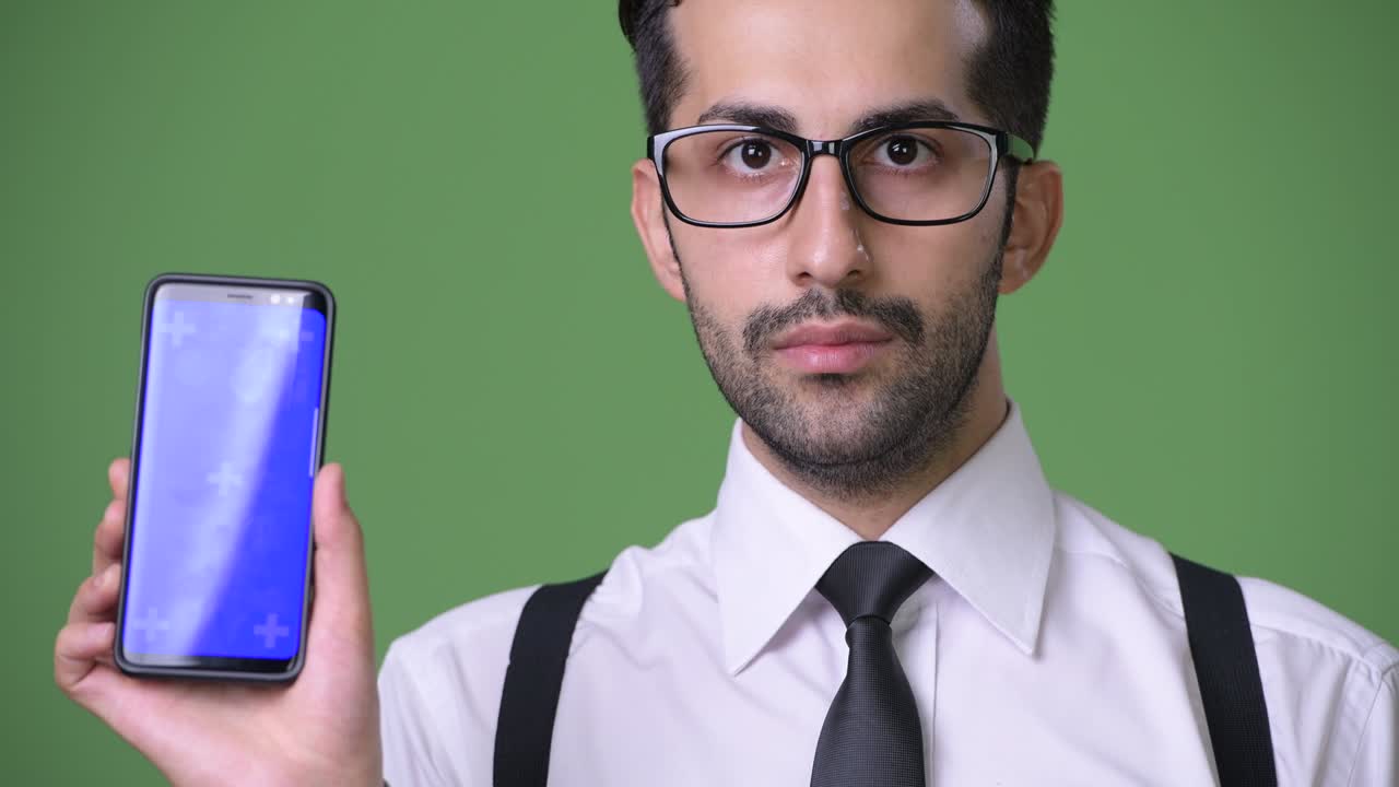 joven empresario persa barbudo y guapo contra un fondo verde