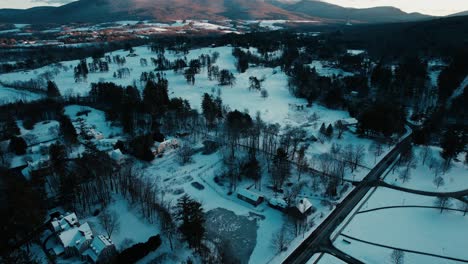 Outward-rotation-centered-on-cottage-with-a-winter-landscape-decorated-with-snowy-scenery-such-as-evergreen-trees,-frozen-ponds,-and-glowing-hillsides-located-in-Williamstown,-Massachusetts,-USA