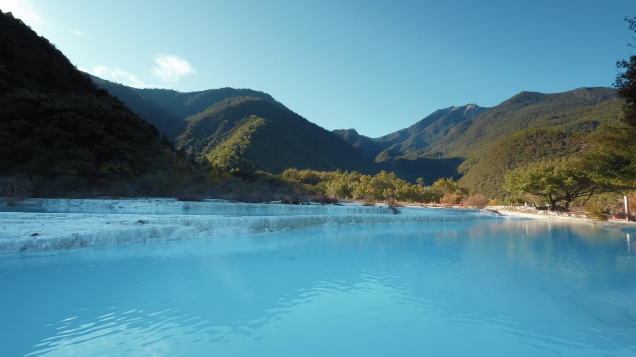 Las brillantes piscinas escalonadas azules de Baishuitai reflejan las montañas y los bosques circundantes, revelando un paisaje sagrado de piedra caliza único en Yunnan, China.