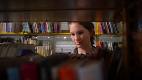 estudiante explorando la biblioteca de la escuela, dando la vuelta a las páginas del libro, de mano