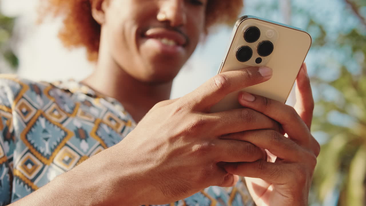 Young Man Smiling While Using Smartphone Outdoors