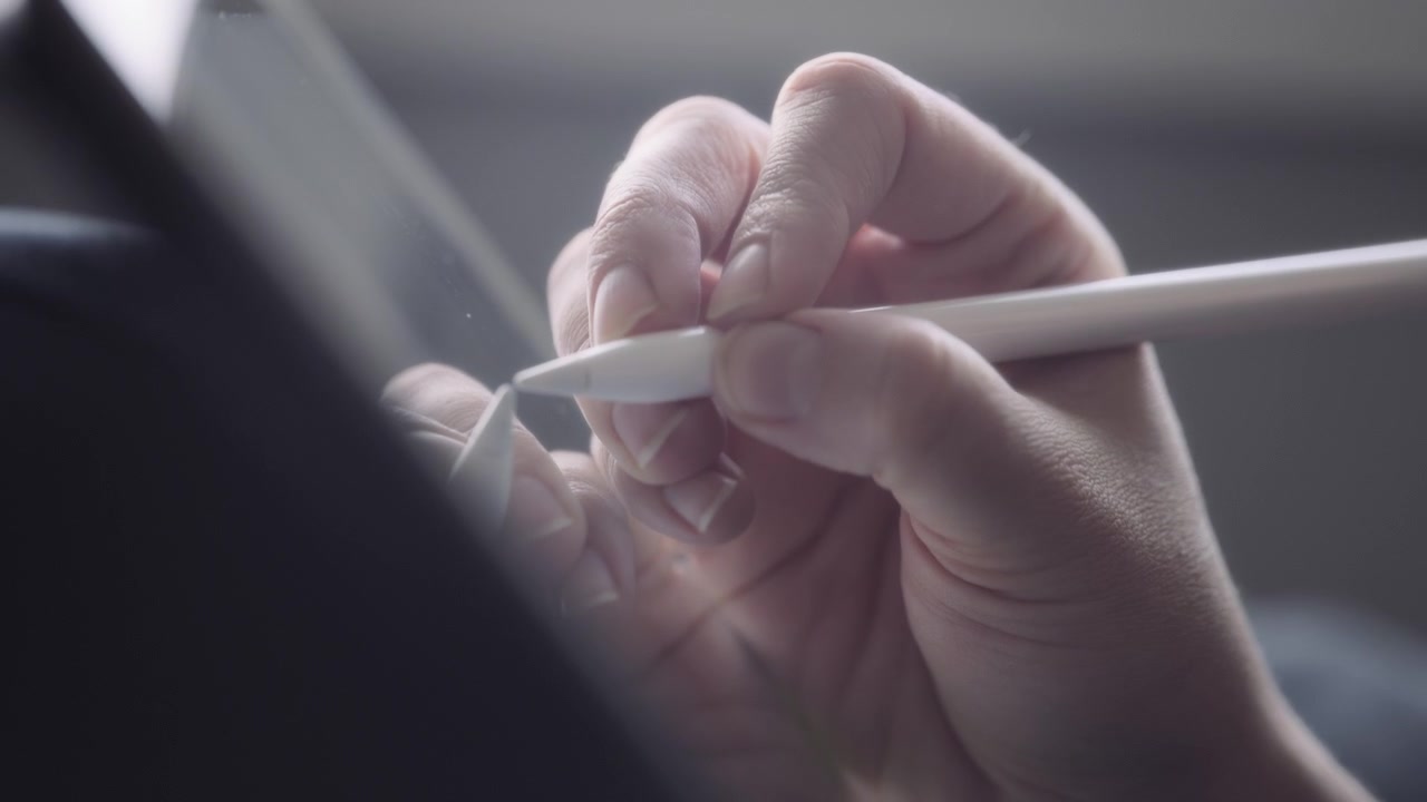 Nærbillede af en kunstners hånd, der tegner på en tablet med en pen